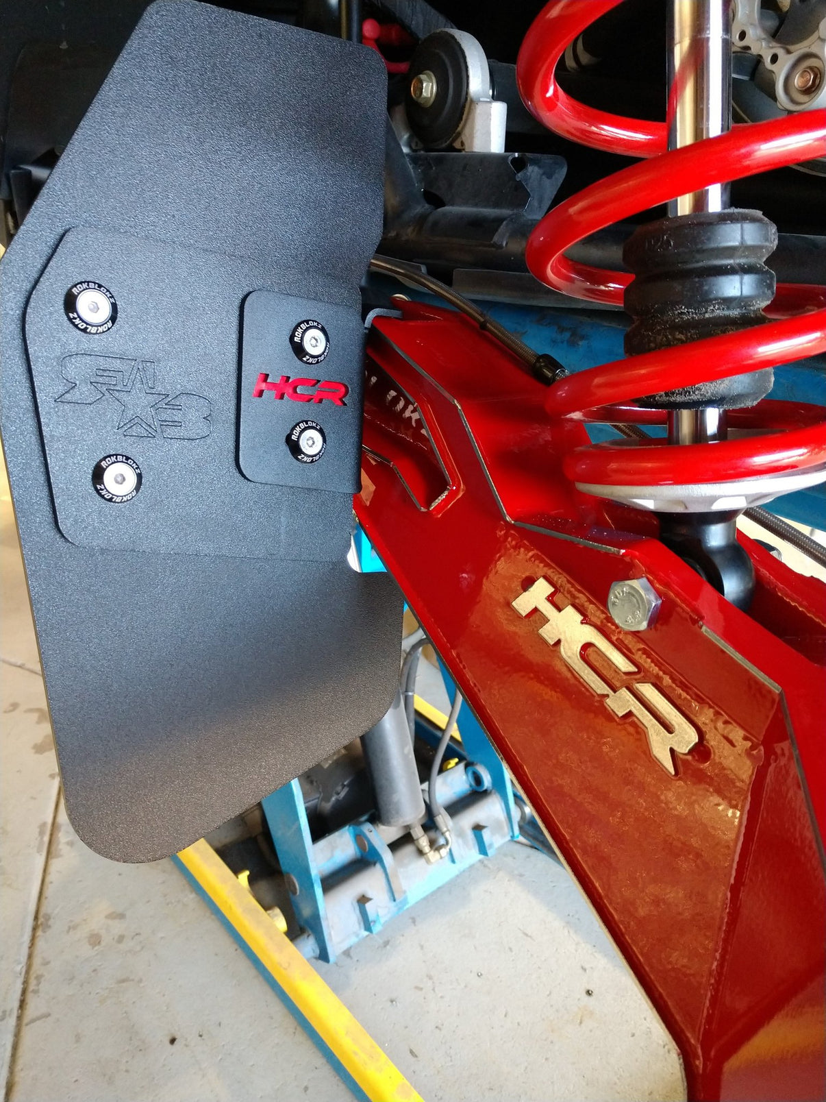 HCR TRAILING ARM MUD FLAPS installed on a UTV with red suspension and black components for off-road protection.